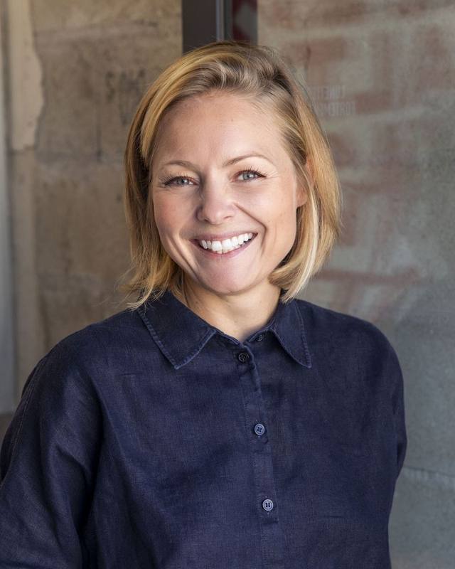 Portrait d'Anne-Sophie Clément, souriante, en chemise bleu marine